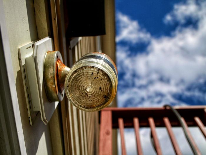 Close-up of metal door by building against sky