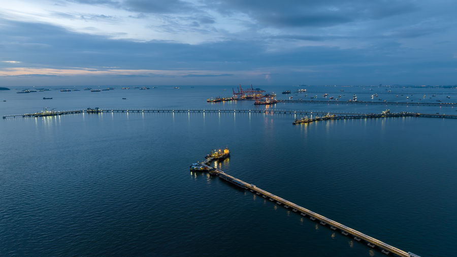 Aerial seascape view and oil and gas pipeline bridge stretched through the sea at twilight 