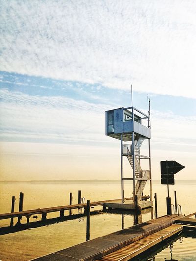 Lifeguard hut on sea against sky during sunset
