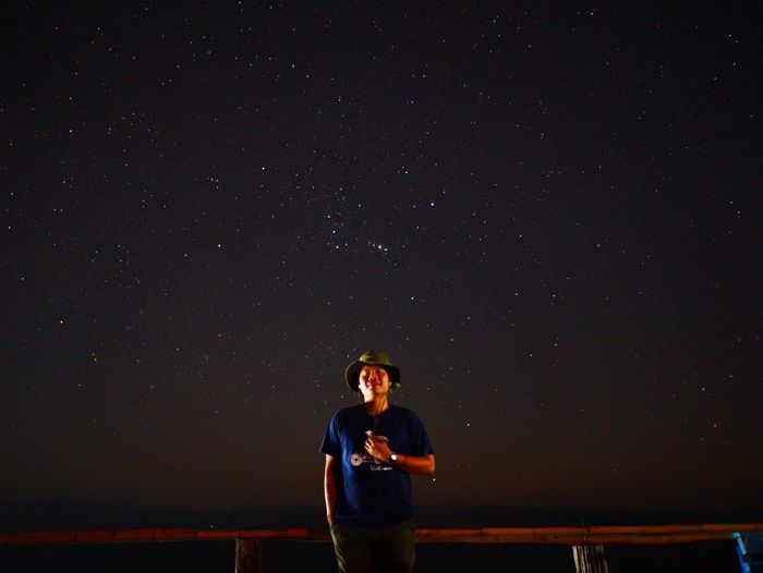 Full length of young man standing against sky at night
