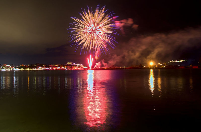 The fireworks paint the sky in various colors and are reflected in the miseno lake.