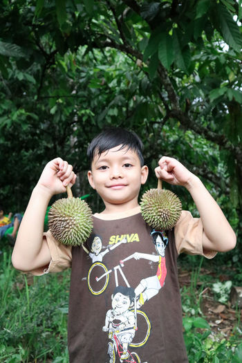 Portrait of smiling boys holding  durian plant