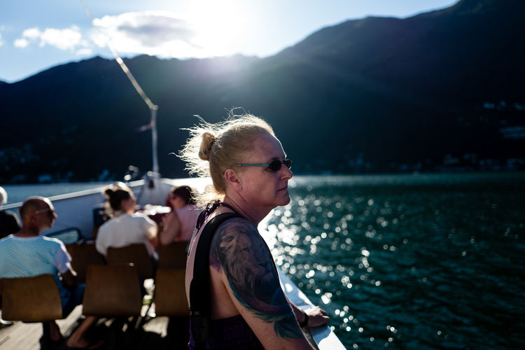 Mature woman standing on boat deck against mountain