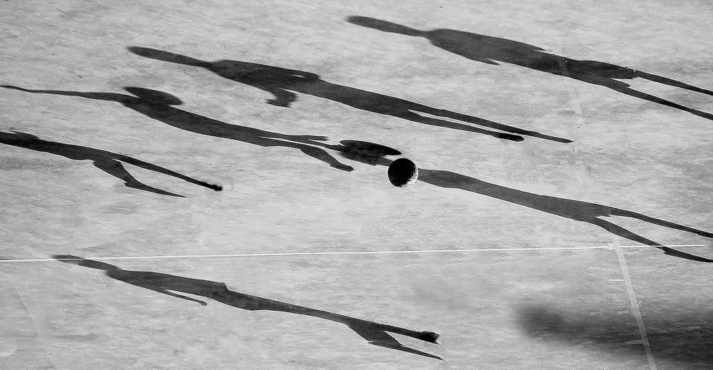 Soccer ball on field with shadows of players