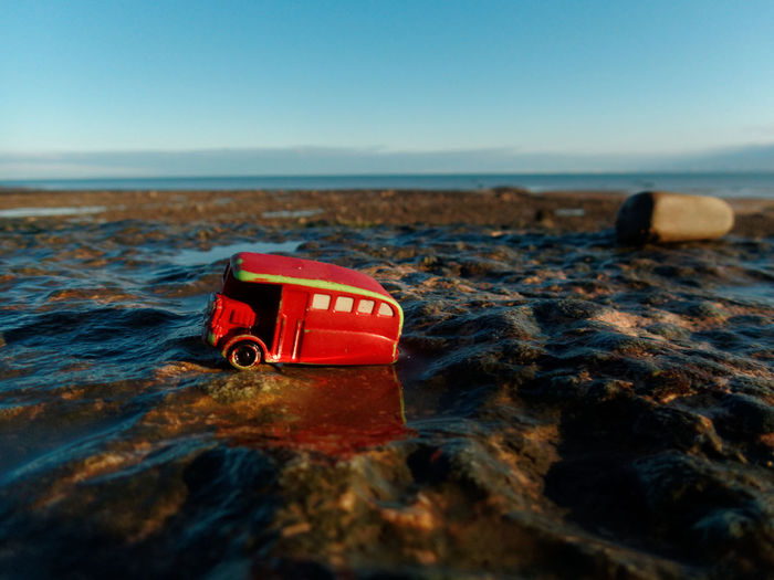 Close-up of red boat on beach against clear sky