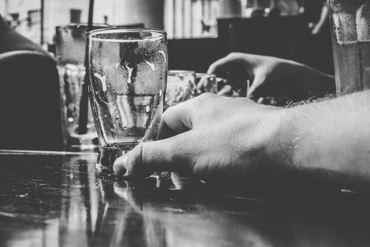 Close-up of cropped man hand holding empty glass on table