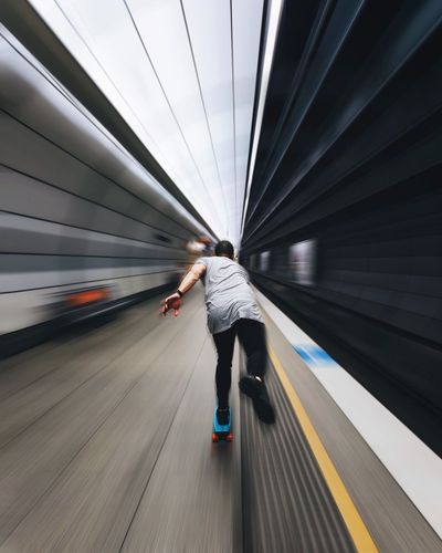 Rear view of skateboarding on subway station platform