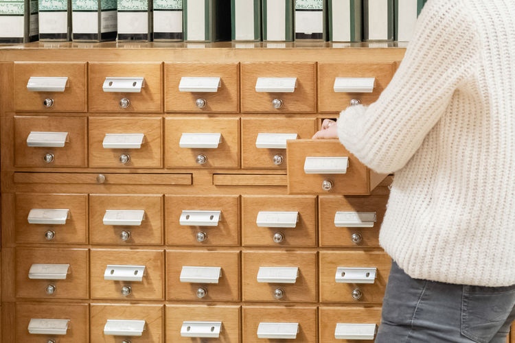 A librarian hand opens library card or file catalog box.