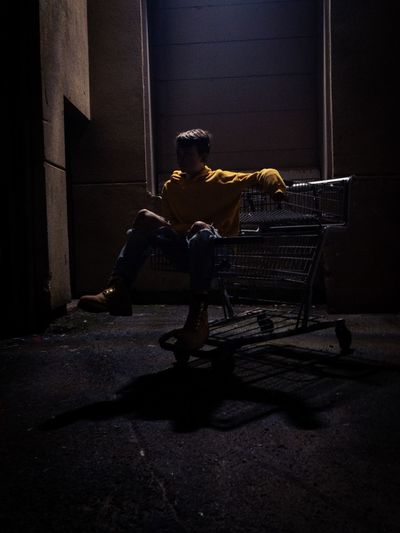 Man sitting in shopping cart on street at night