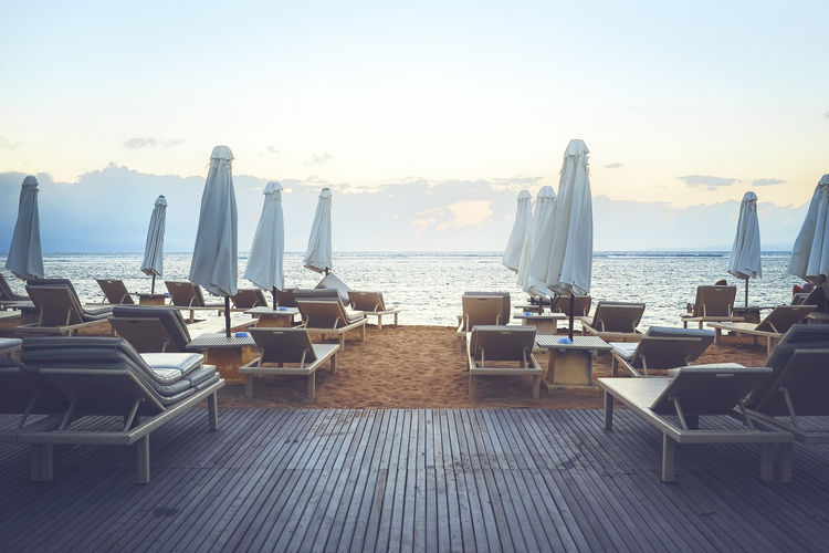 Chairs and table by sea against clear sky