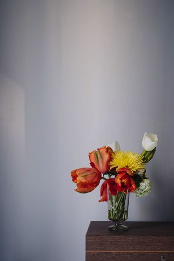 Close-up of orange flower vase on table against wall