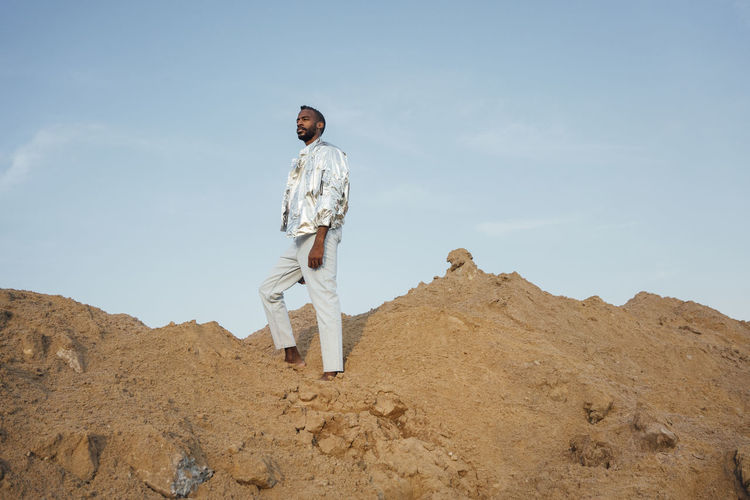Man wearing silver jacket standing on sand