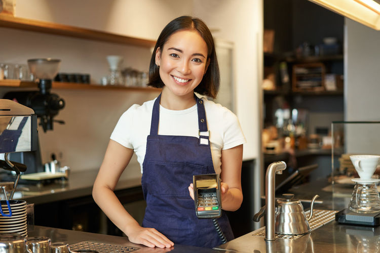 Portrait of smiling young woman standing in kitchen