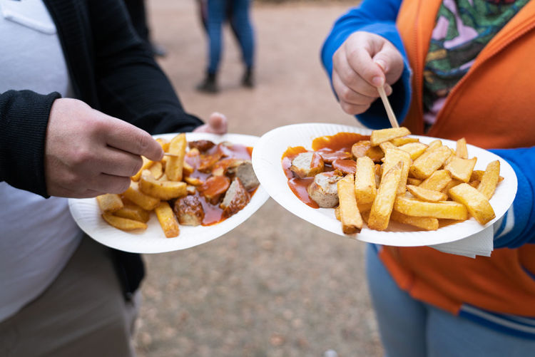 Couple with two paper plates with french fries and currywurst