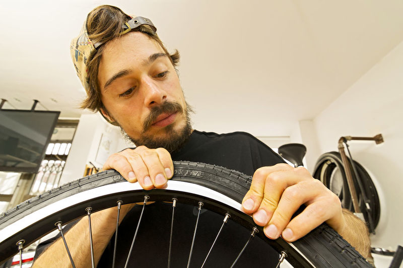 Low angle view of young man repairing bicycle tire in workshop