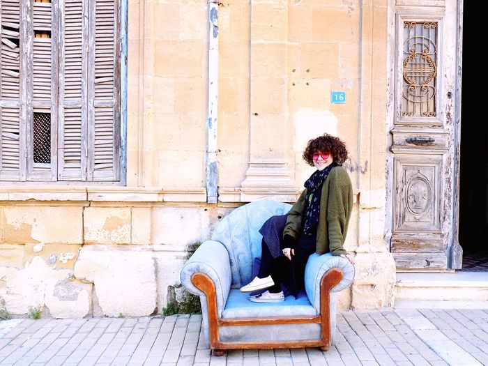 Portrait of woman sitting on chair by old wall