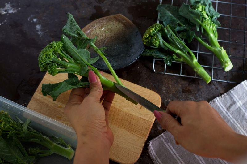 Cropped hands of woman cutting broccoli