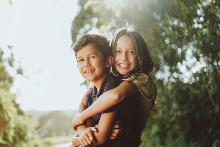 Portrait of smiling sibling embracing outdoors