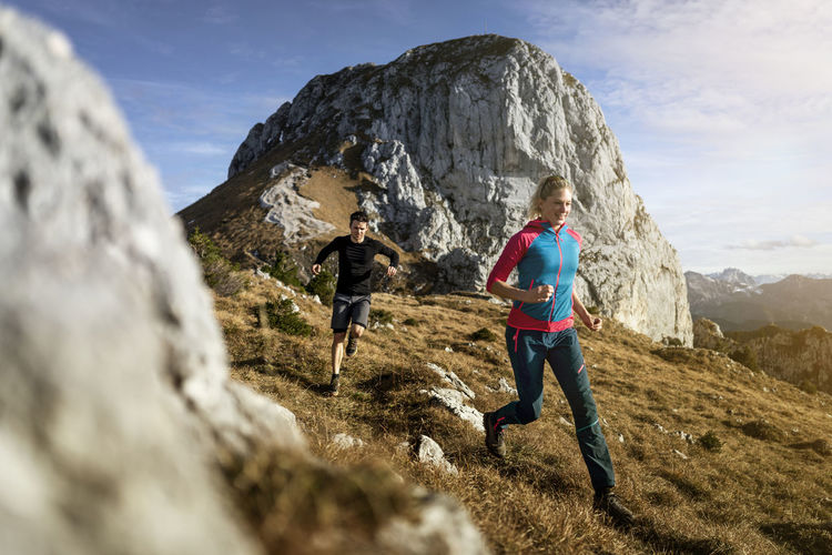 Sportsman and woman running on saulingspitze mountain at bavaria, germany