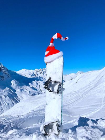Santa hat on equipment at snowcapped mountain against clear blue sky