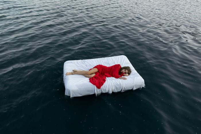 Young woman sleeping on bed floating in lake