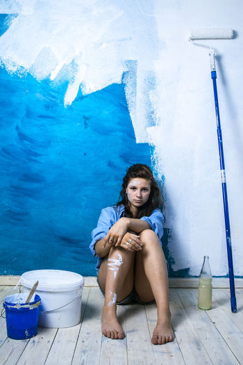 Portrait of young woman sitting by wall
