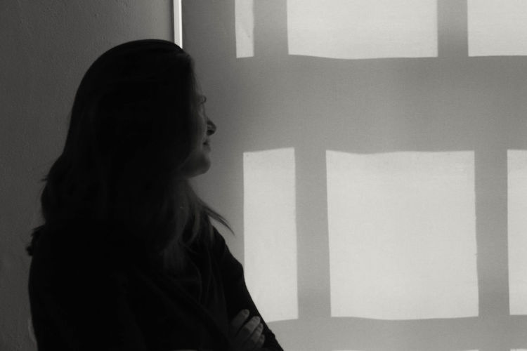 Close-up of pensive woman standing by window at home