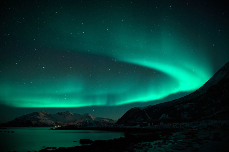 Scenic view of snowcapped mountains and aurora borealis against sky at night