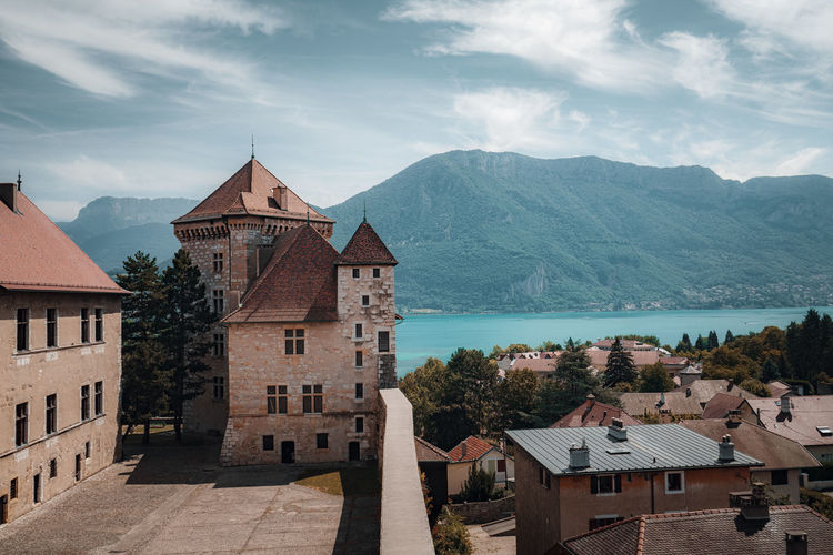 Castle in town in front of lake against mountain and sky