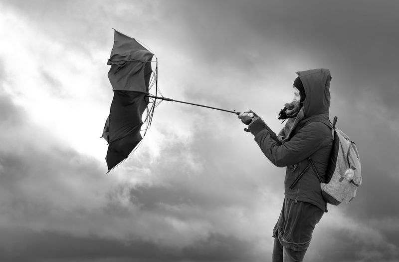 Low angle view of man holding umbrella against sky