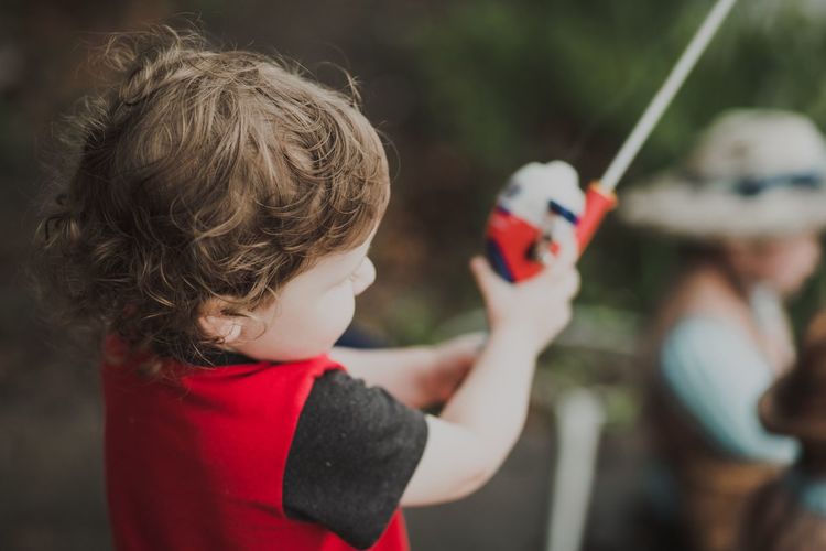 Close-up of boy holding fishing rod while standing outdoors