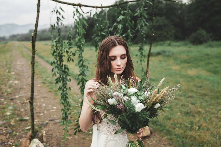Young woman standing with flower bouquet on field
