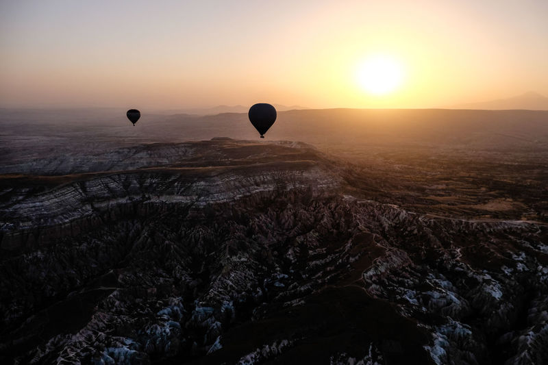Hot air balloons flying over landscape against sky during sunrise 