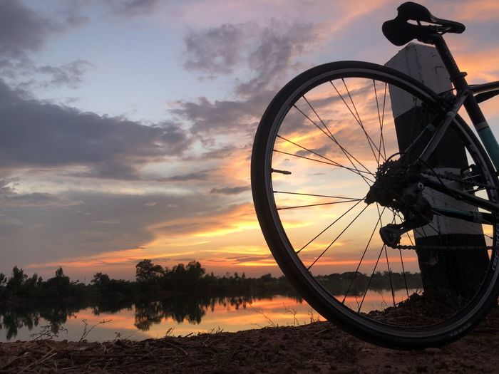 Silhouette bicycle wheel against sky during sunset