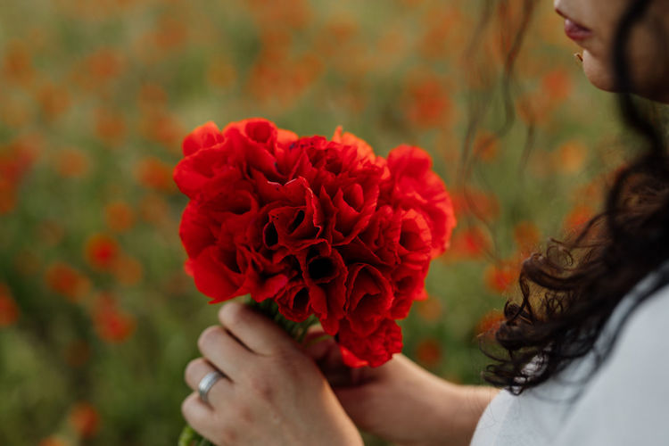 Midsection of woman holding red flower