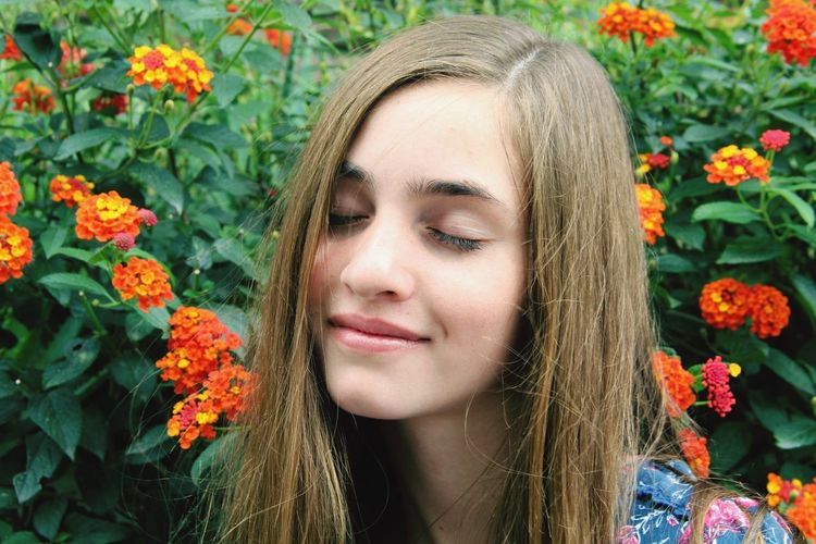 Close-up of young woman with eyes closed by lantana camara