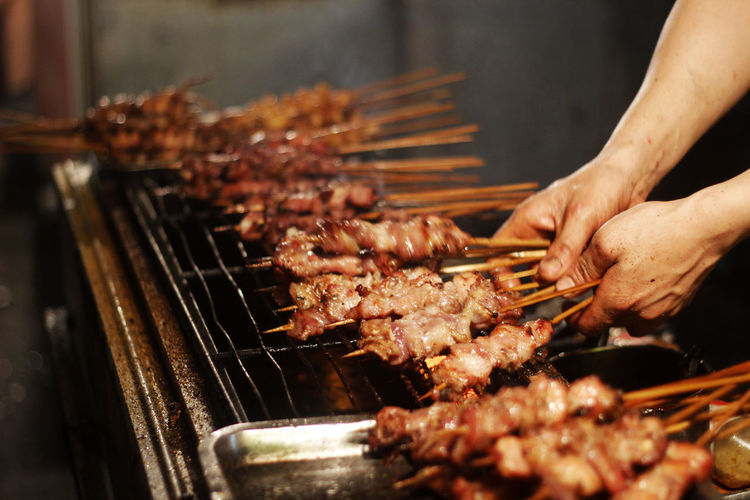 Person preparing food on barbecue grill