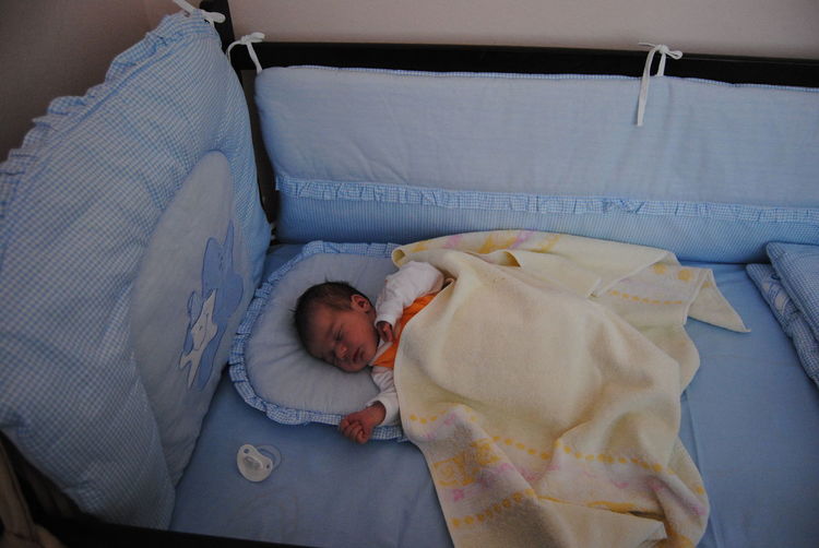High angle view of child lying in crib