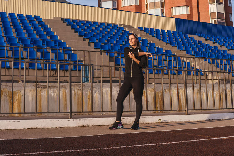 Full length of woman exercising while standing in stadium