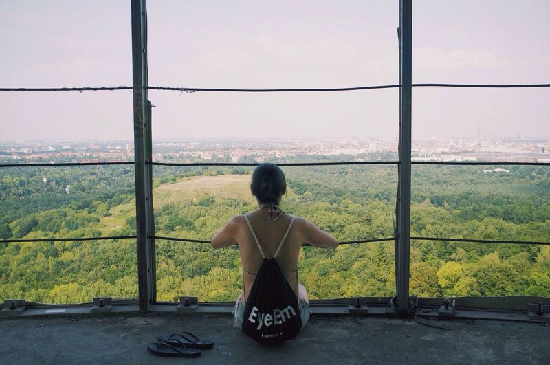 Rear view of woman sitting at an observation point looking at a view