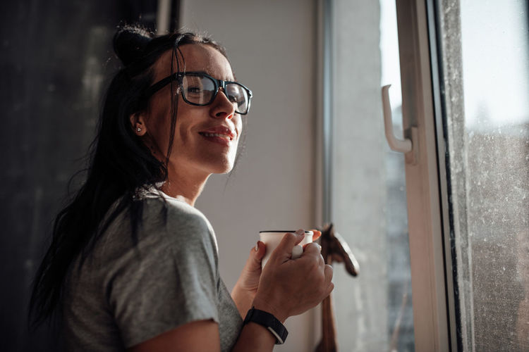 Portrait of woman wearing sunglasses against window