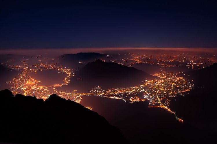 Scenic view of mountains and illuminated cityscape against sky night