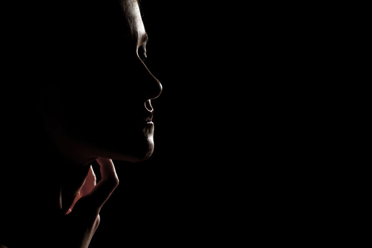 Sad female profile silhouette on black background with copy space, closed eyes