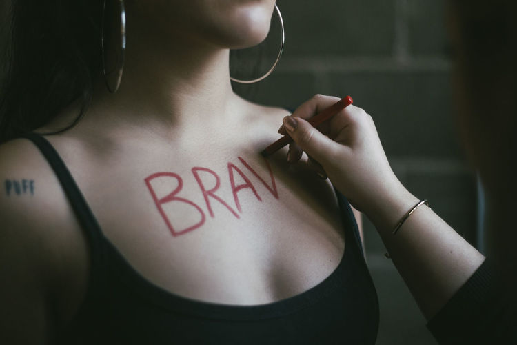 Cropped hand of woman writing on female activist's chest