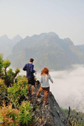 Rear view of couple standing on mountain against clear sky