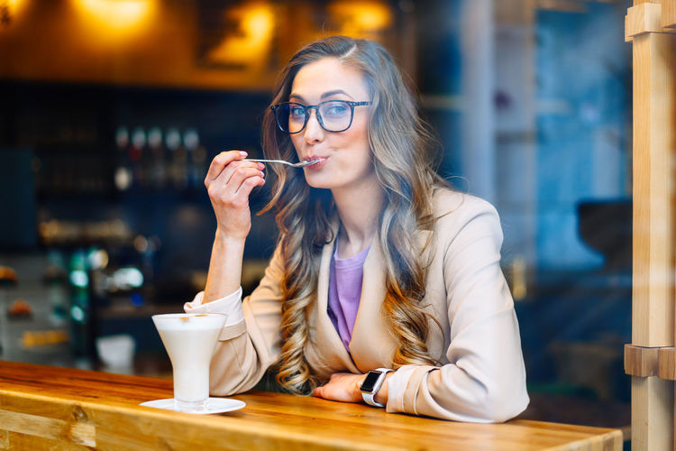 Portrait of smiling woman having drink while sitting at cafe