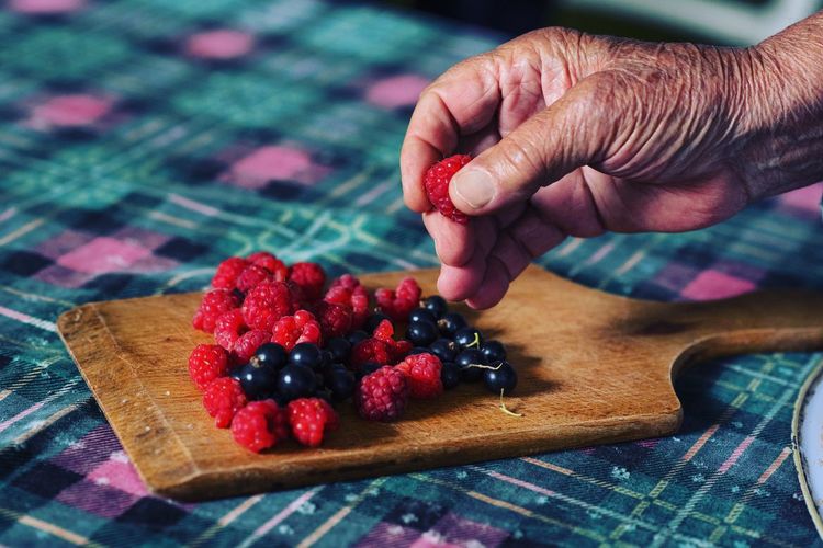 Cropped hand arranging berries on serving board