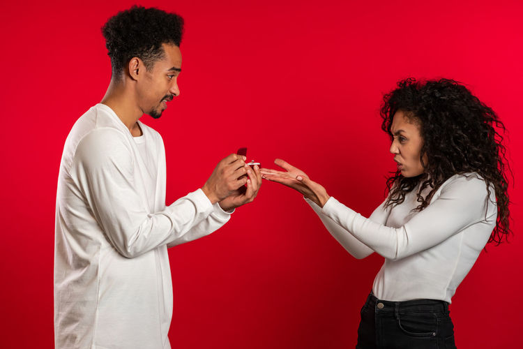 Young couple standing against red background