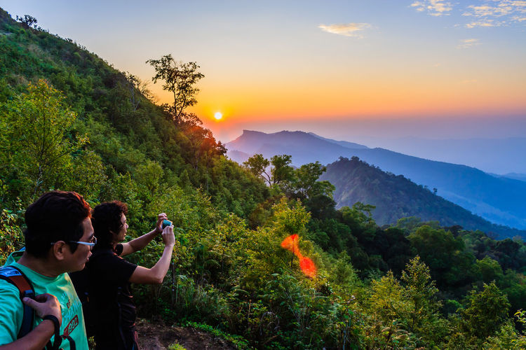 Man photographing mountains during sunset