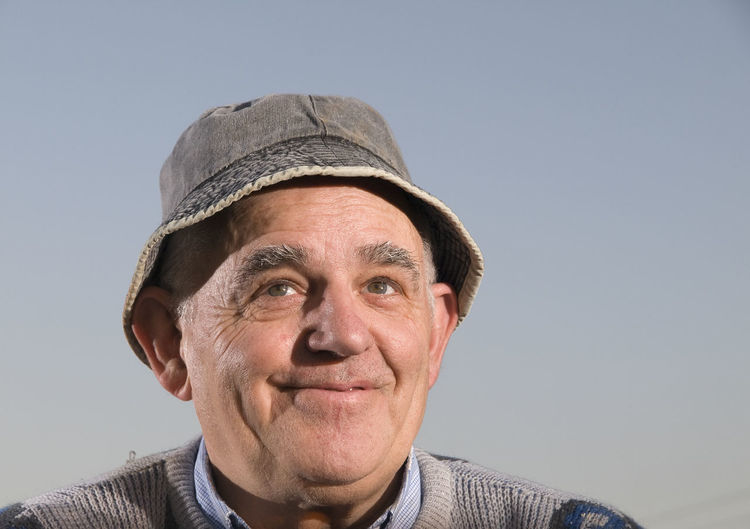 Close-up of senior man wearing hat against clear sky